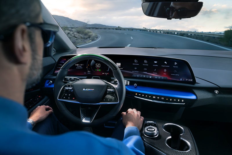 Front View of the 2026 OPTIQ-V Driving Through the Dusk Utilizing its Headlights | Seaside Cadillac in SEASIDE CA