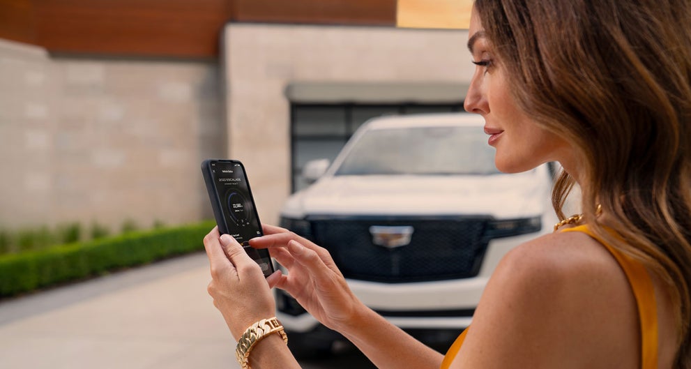 lady checking her mobile with a Cadillac vehicle background | Seaside Cadillac in SEASIDE CA